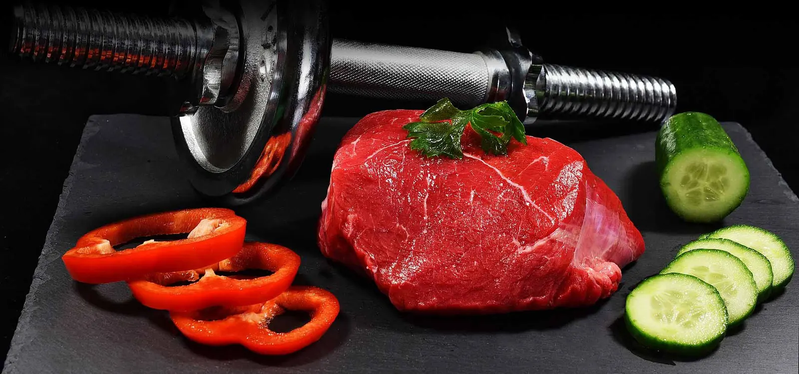 Lean steak, cucumber and peppers next to a dumbbell representing nutrition for home workouts