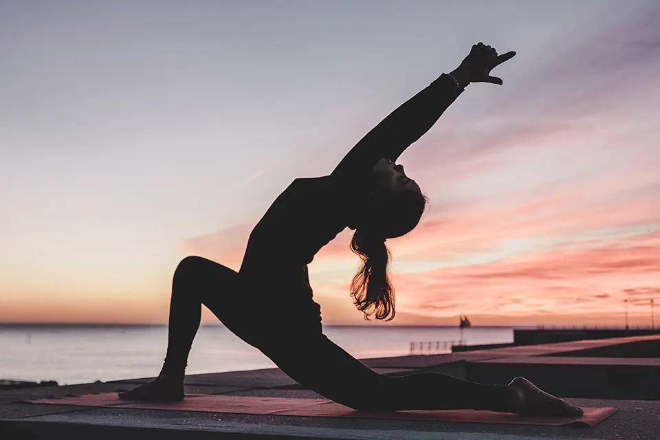 Woman doing a low lunge stretch at sunset as part of a mobility routine